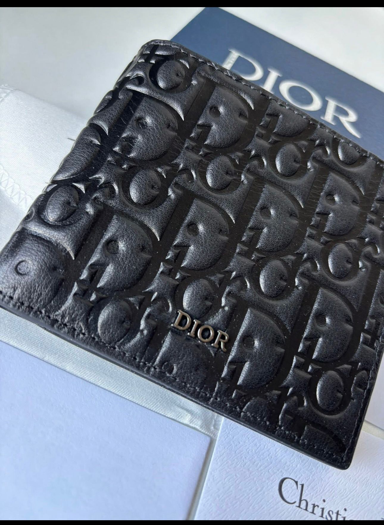 Dior bifold wallet crafted from black leather, featuring an embossed Dior Oblique or Dior Gravity motif