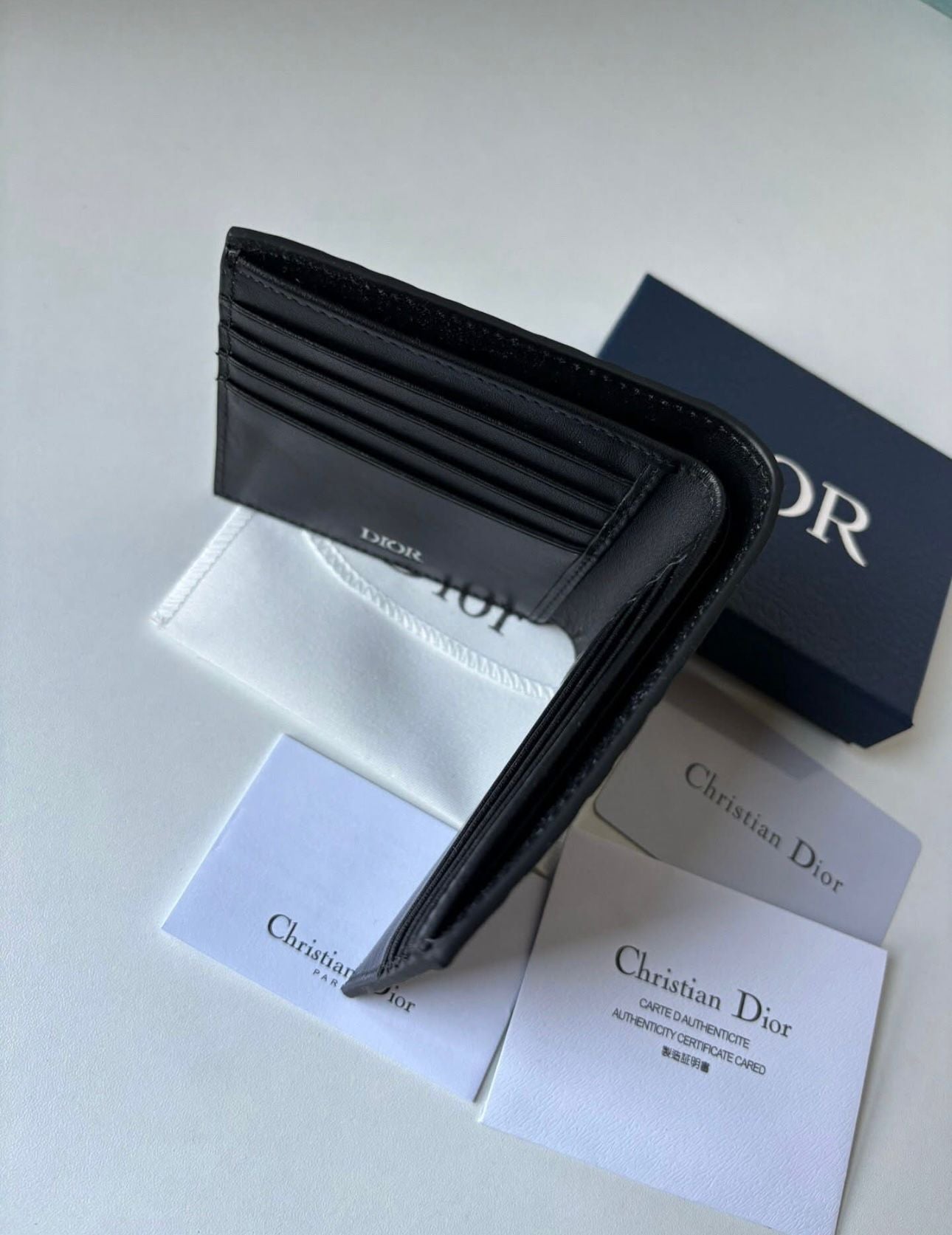 Dior bifold wallet crafted from black leather, featuring an embossed Dior Oblique or Dior Gravity motif