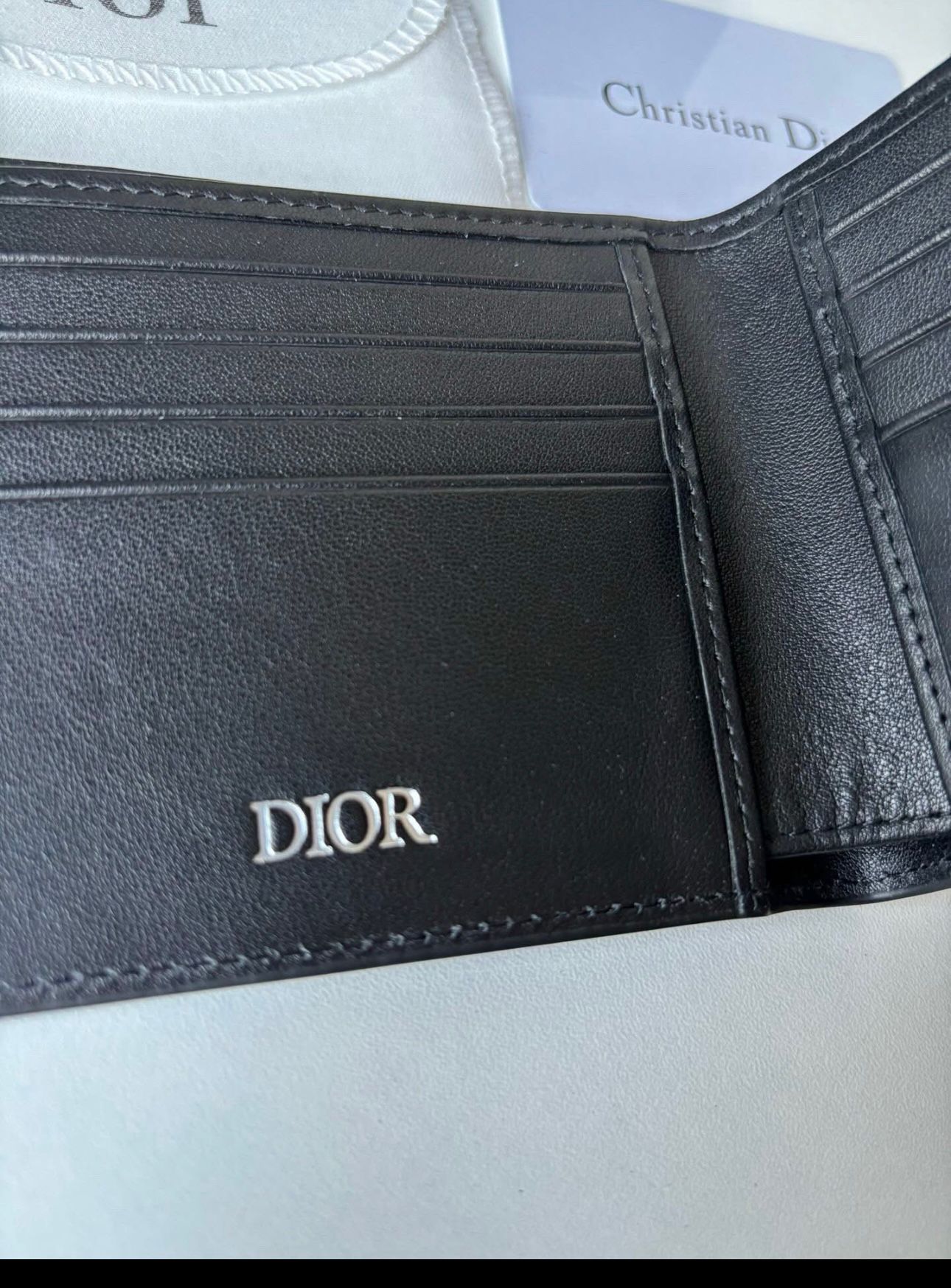 Dior bifold wallet crafted from black leather, featuring an embossed Dior Oblique or Dior Gravity motif