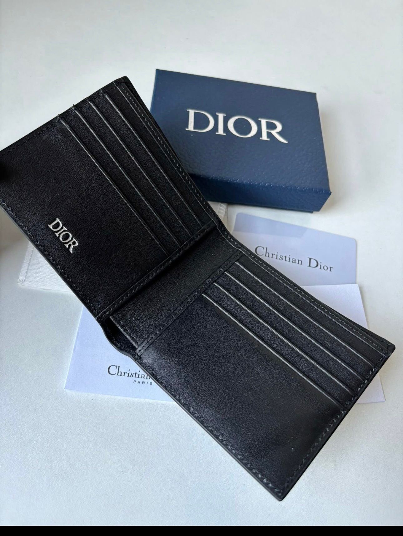 Dior bifold wallet crafted from black leather, featuring an embossed Dior Oblique or Dior Gravity motif